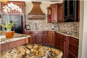 Kitchen Island with Golden Crystal Granite Paired with Stone Radiance Tile Backsplash, Ornamental Granite Countertops and Saddle Brown Cabinets